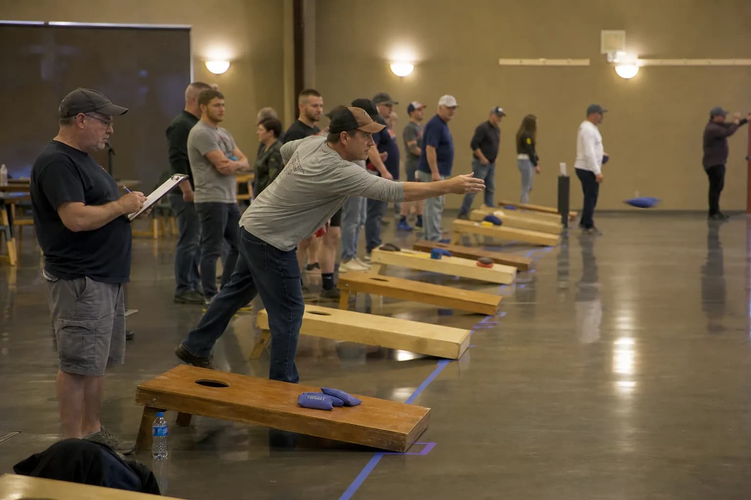 Players throwing bags at an indoor cornhole league night