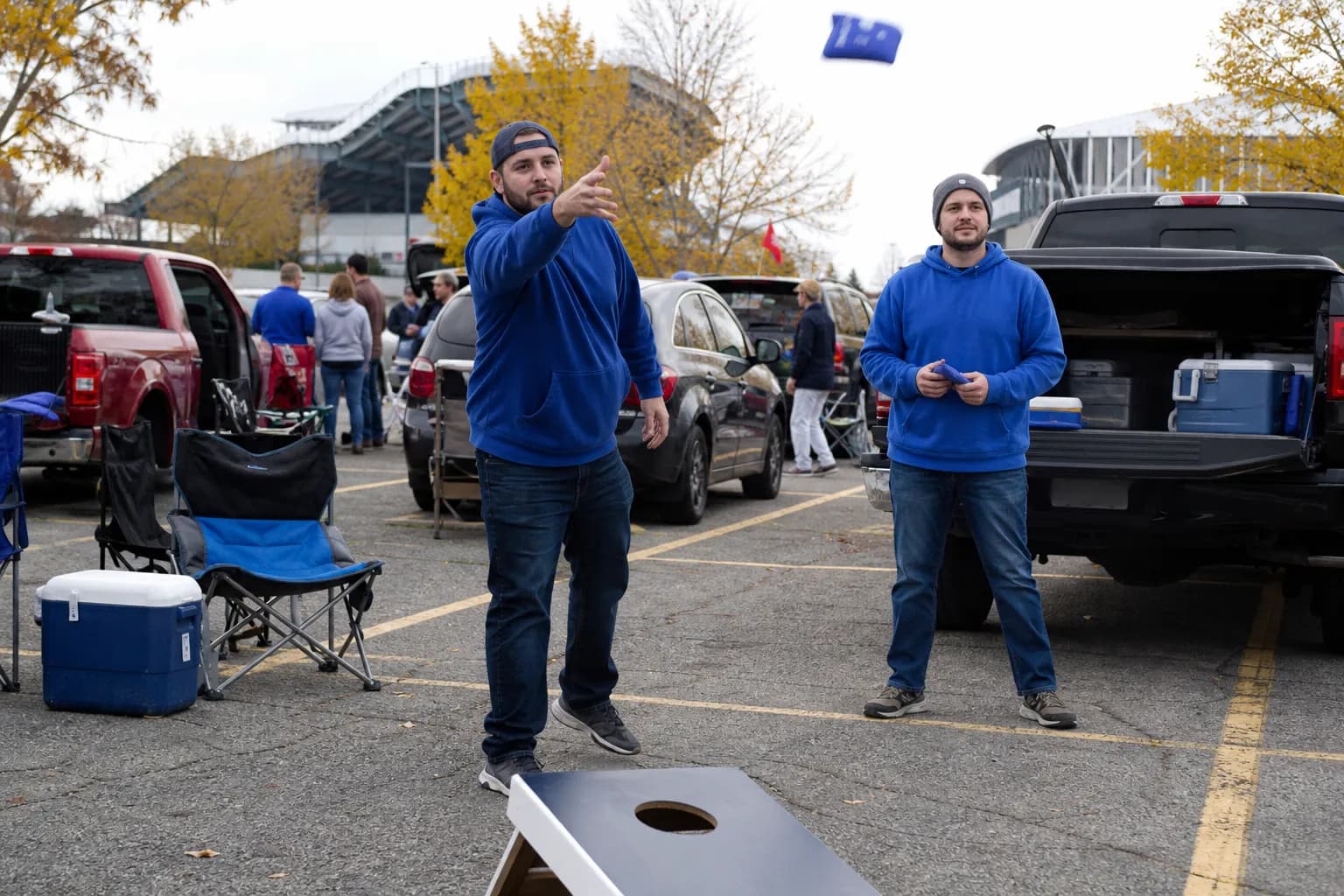 Friends playing cornhole at an autumn tailgate