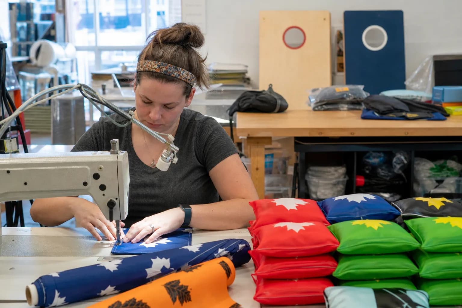 A worker sewing custom cornhole bags in a workshop